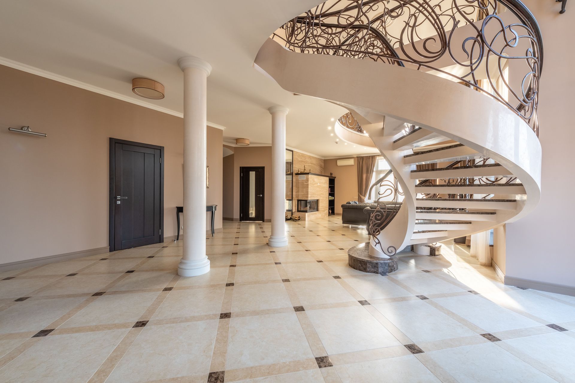 Interior of spacious room with spiral stairway on tiled floor and white columns near doors of contemporary building with creative design
