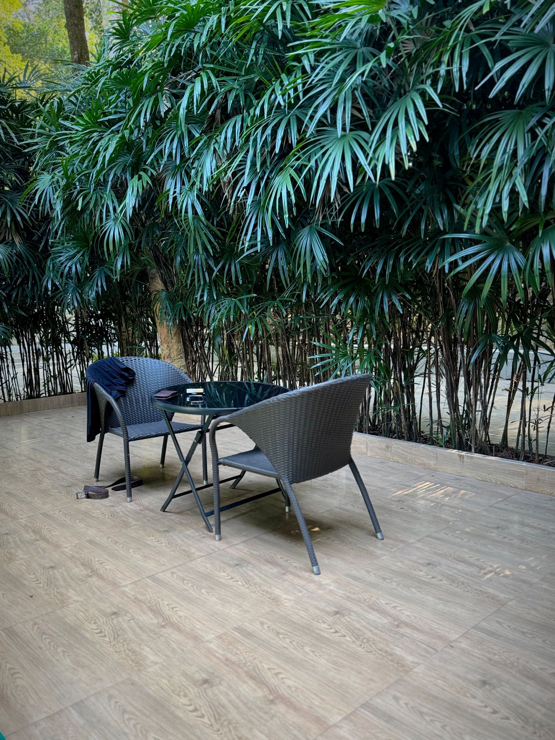 Cozy outdoor patio with wicker chairs, wooden flooring, and lush foliage creating a serene atmosphere.