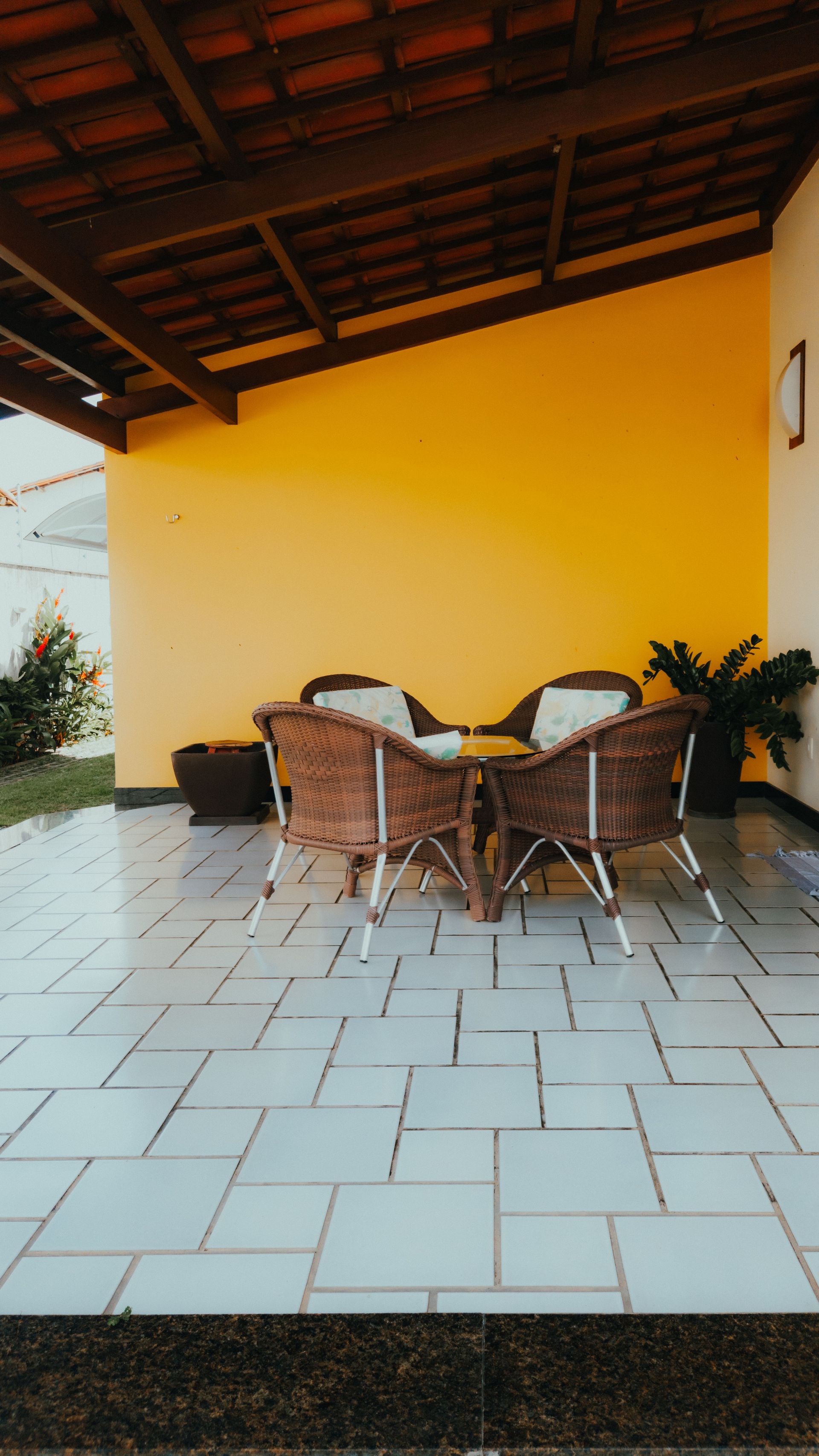 Inviting outdoor patio with rattan furniture set under a wooden roof, ideal for relaxation.