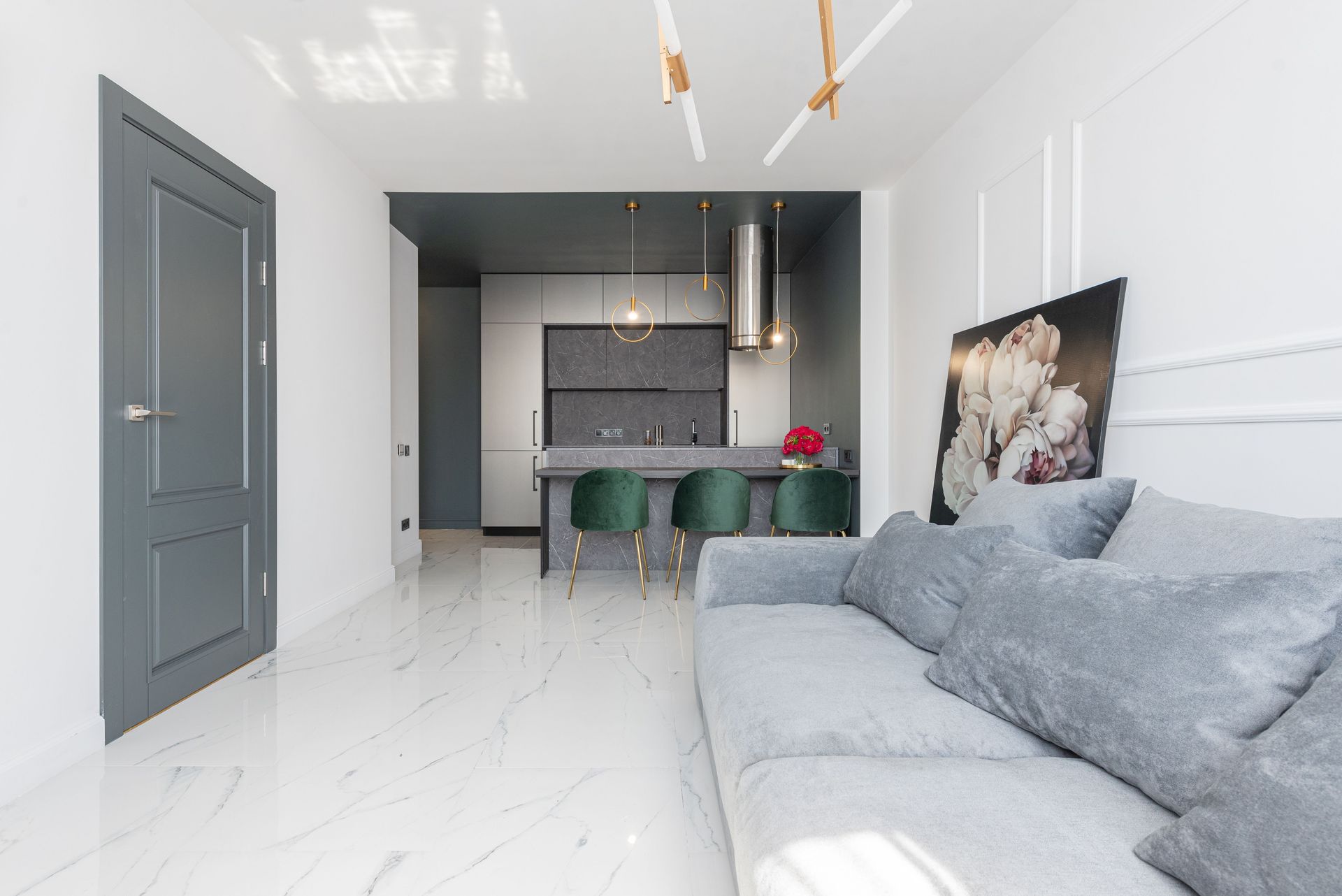 Contemporary studio apartment furnished with soft couch in living zone and armchairs and cupboards in kitchen