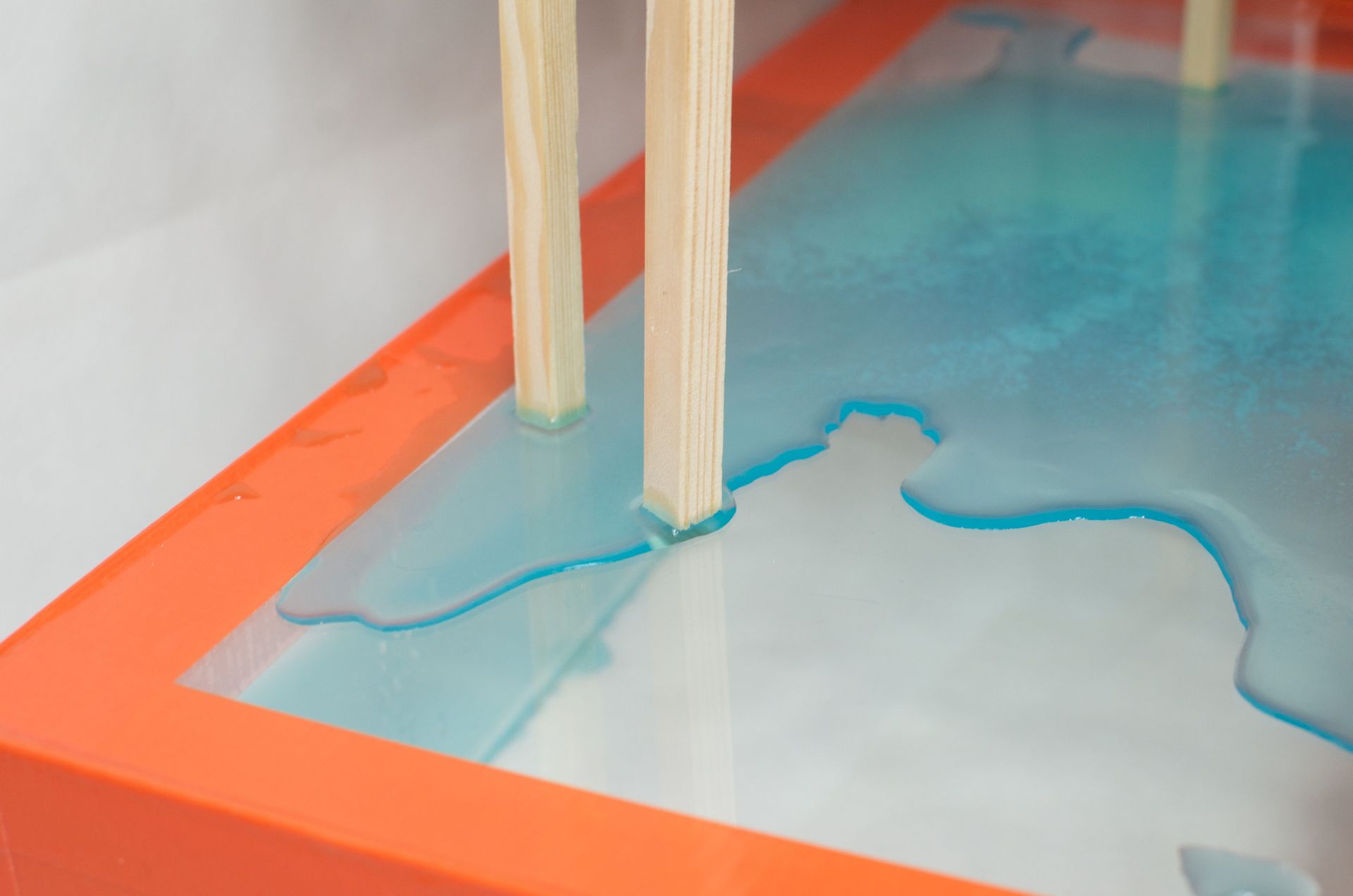 High angle of timber object placed above transparent glass with colored water as art installation