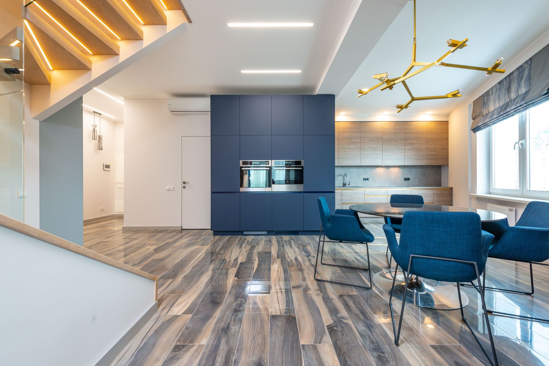 Table with armchairs on floor against cabinets and built in electric appliances in modern kitchen at home